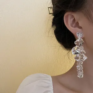 Detailed close-up of transparent irregular ice cube drop earrings worn by a model