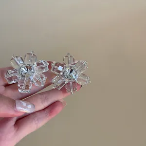 Close-up of transparent irregular ice cube flower earrings with silver needles.