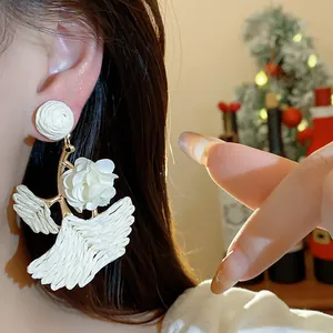 Detail of white raffia ginkgo leaf earring with delicate fabric flower accent