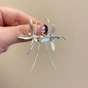 Dettaglio di orecchini a forma di iris in argento opaco con lunghi ganci curvi eleganti