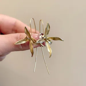 Dettaglio di orecchini a gancio a forma di iris dorati vintage con petali opachi.