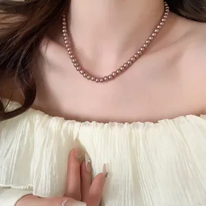 Close-up detail of an elegant dusty rose pearl necklace shown on a female neck
