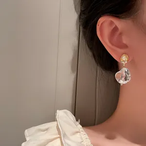 Detailed view of elegant gold-tone earrings with transparent irregular ice cube drops