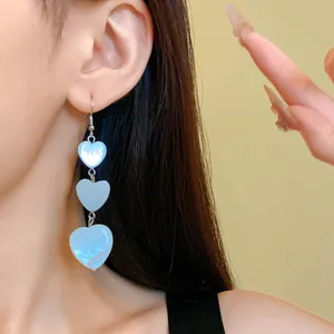Close-up of elegant triple heart dangle earrings with iridescent shell-like luster