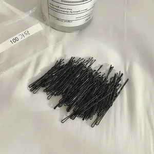 Set di 100 forcine nere minimaliste per capelli su sfondo di tessuto bianco