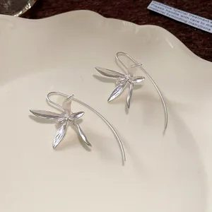 Macro di eleganti orecchini a gancio con fiori di iris in argento su un piatto di ceramica