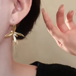 Dettaglio delle eleganti orecchini a fiore di iris dorati indossati da una modella