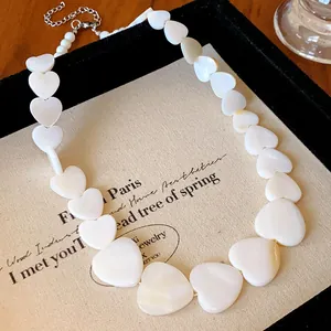 Close-up detail of white iridescent heart-shaped shell beads on a minimalist necklace