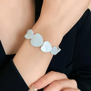 Close-up of a minimalist white heart-shaped shell bracelet worn on a woman's wrist