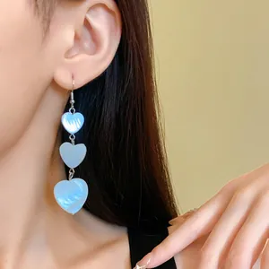Detailed close-up view of triple-layered heart-shaped dangling earrings worn by model