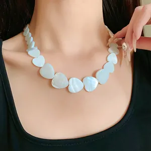 Close-up detail of a minimalist white heart-shaped shell necklace worn on a model's neck