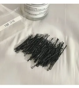 Dettaglio di un set di 100 forcine per capelli nere minimaliste per lo styling dei capelli