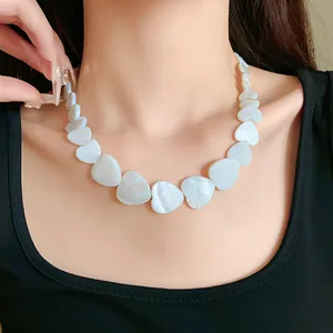 Close-up detail of a minimalist iridescent heart-shaped shell choker necklace on neck