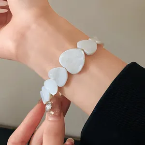 Detailed view of an elegant white heart-shaped link necklace worn on a person's wrist