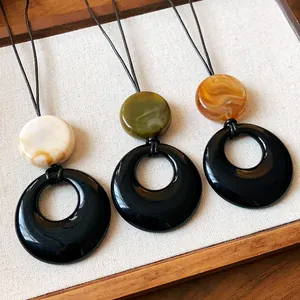 Close-up of three elegant resin circular necklaces featuring marble texture pendants