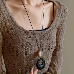 Close-up of a resin ring pendant necklace on a long cord over a knit sweater