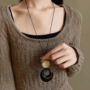 Detailed view of a vintage resin ring pendant necklace worn as a long sweater chain