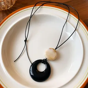 Detailed close-up of resin ring and marble bead pendant on a vintage style cord necklace