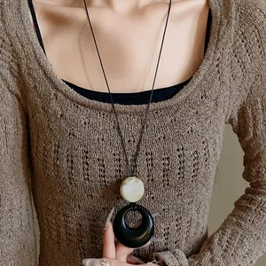 Detail view of a stylish resin double ring pendant necklace on a minimalist long black cord