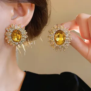 Dettaglio di orecchini a lobo a girasole dorati con cristallo giallo e diamanti scintillanti