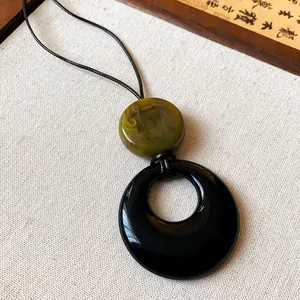 Close-up detail of a New Chinese style resin pendant necklace with a black ring and green bead