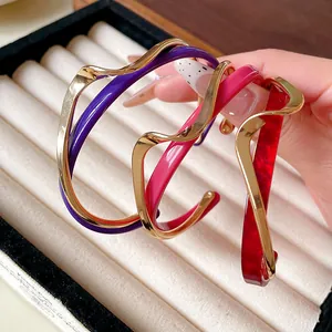 Detalle de tres pulseras de acrílico de doble capa con forma de onda y baño de oro.