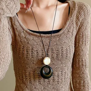 Close-up of a new Chinese style resin ring long necklace worn with a brown sweater.