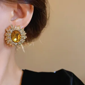 Dettaglio di orecchini a lobo a girasole dorati con cristallo ambra e strass brillanti