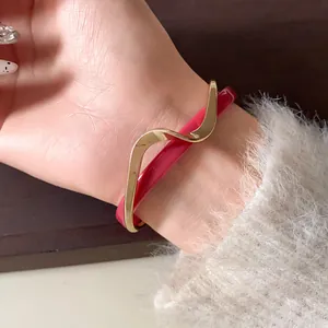 Primer plano de un brazalete abierto de doble capa en acrílico rosa y chapado en oro ondulado