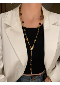 Close-up of a vintage tiger eye beaded long necklace on a model wearing a stylish white blazer