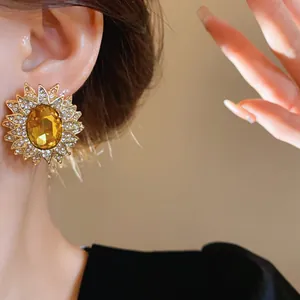 Dettaglio di un orecchino a forma di girasole dorato con grande cristallo ambrato centrale
