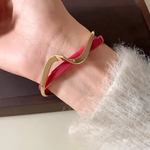 Detalle del brazalete de doble capa con baño de oro ondulado y acrílico rojo