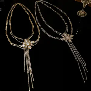 Detailed view of gold and silver pearl flower body chains with long tassels on black background.