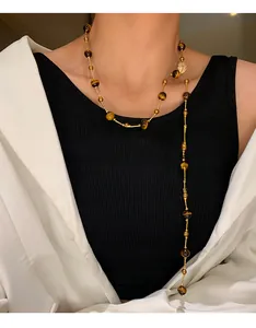 Macro view of a long vintage tiger eye beaded necklace on a model wearing a black top