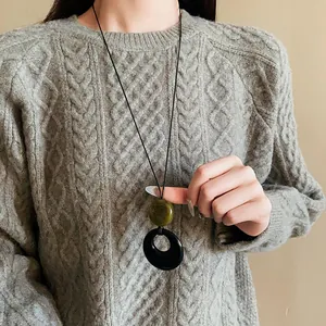 Detail view of a long resin ring necklace paired with a cozy grey knitted sweater