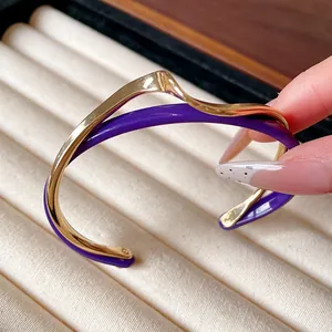 Detalle de un brazalete ondulado de doble capa chapado en oro y acrílico morado minimalista
