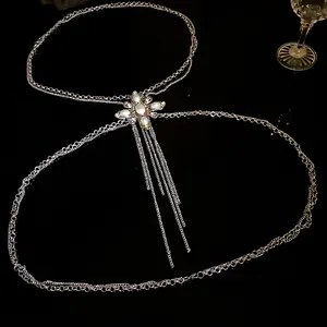 Detailed view of rhinestone and pearl body chain on a sleek black surface