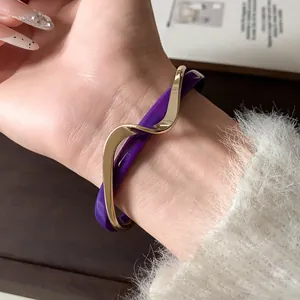 Primer plano detallado de un brazalete abierto de ondas en acrílico púrpura y oro