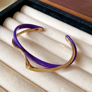 Primer plano de un brazalete de doble capa con ondas doradas y moradas en un joyero