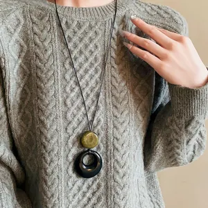Detailed view of a vintage resin ring necklace worn on a minimalist textured grey sweater.