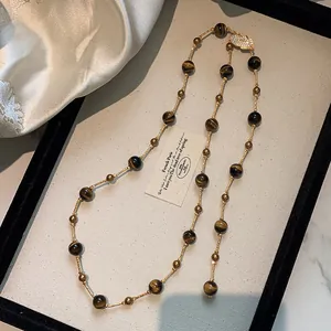 Close-up of tiger eye bead necklace with gold spacers and leaf clasp on display tray