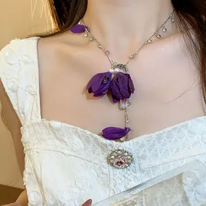 Close-up detail of a purple fabric flower necklace with elegant rhinestones and pearl accents.