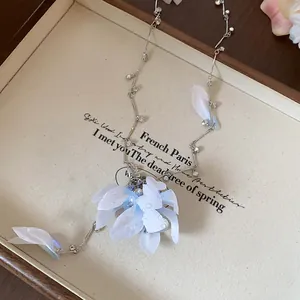 Detail view of an elegant fabric flower necklace with rhinestones and soft blue petals.