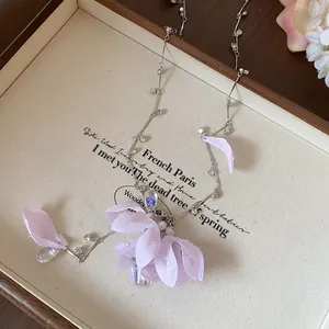 Detailed view of light purple fabric flower charms and iridescent crystals on necklace