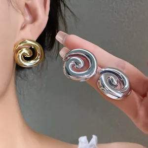 Close-up of glossy silver and gold spiral geometric stud earrings with metallic finish