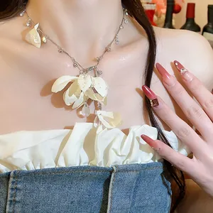 Close-up detail of a delicate rhinestone water-drop cloth flower necklace on model neck