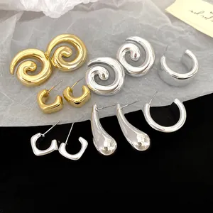 Variety of gold and silver geometric stud and hoop earrings set on black and white backdrop