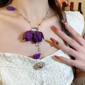 Detailed close-up of a purple fabric flower necklace with pearls and elegant rhinestones