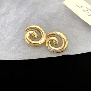 Detailed close-up of golden spiral stud earrings with smooth finish and retro style