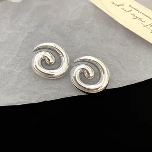Detailed macro view of silver-toned spiral geometric acrylic stud earrings with smooth finish